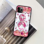 Flat lay of a personalized jeweled pink ribbon case on a book, featuring silver geometric patterns and pink gem borders.