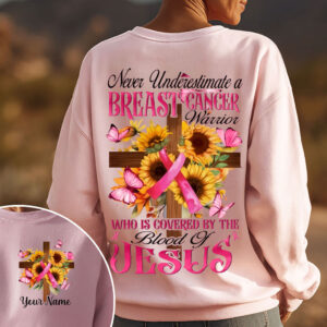 Back view of a pink breast cancer warrior sweatshirt with a cross, sunflowers, and Jesus text worn outdoors.