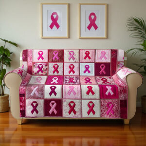 Quilted sofa cover in pink tones features breast cancer awareness ribbons, shown from the front on a cozy couch.