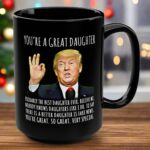 Front view of the black mug featuring 'you're a great daughter' text and a Trump illustration.