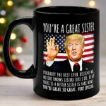 Close-up of the you're a great sister mug featuring a black finish and vibrant Trump design against a flag backdrop.