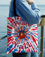 Front view of the peace y'all sunflower america tote bag with vibrant tie-dye colors and bold lettering.