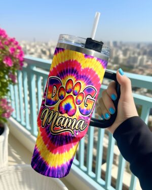 Colorful dog mama paw print swirl tumbler held in hand with a vibrant tie-dye design overlooking a city view.