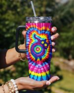 Colorful swirl pattern tumbler with a vibrant cat design, showcased from the front in a sunny outdoor setting.