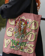 Front view of the good good vibes skeleton tote bag with colorful floral design on a pink background.