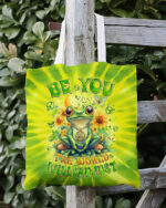 Front view of the be you the world will adjust frog tote bag featuring vibrant tie-dye colors and a cheerful frog design.