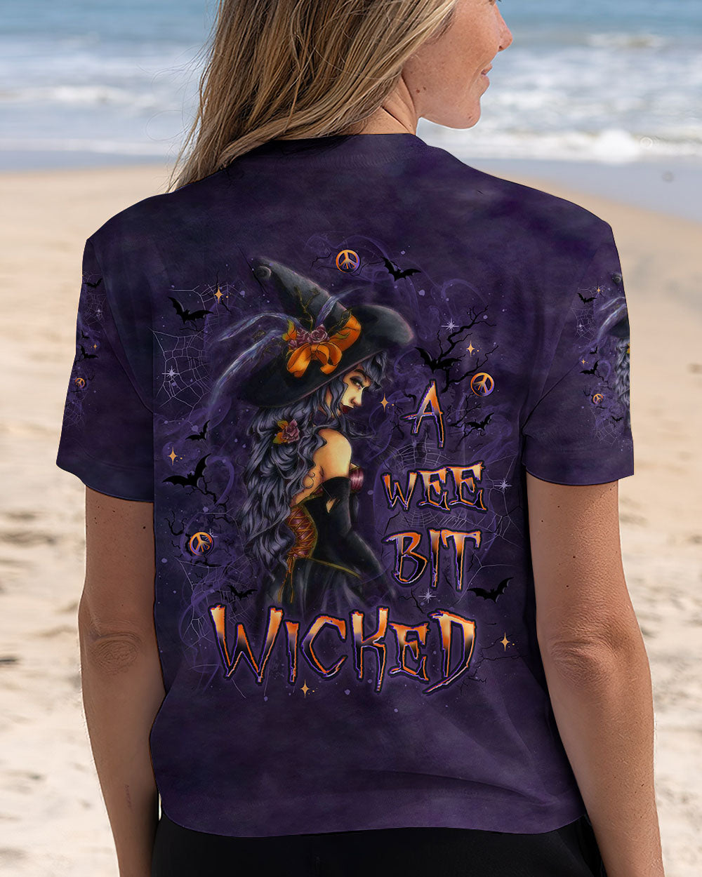 A Wee Bit Wicked Witch Shirt | All Over Print Lifestyle shot of a person wearing the a wee bit wicked witch shirt outdoors, perfect for Halloween festivities.