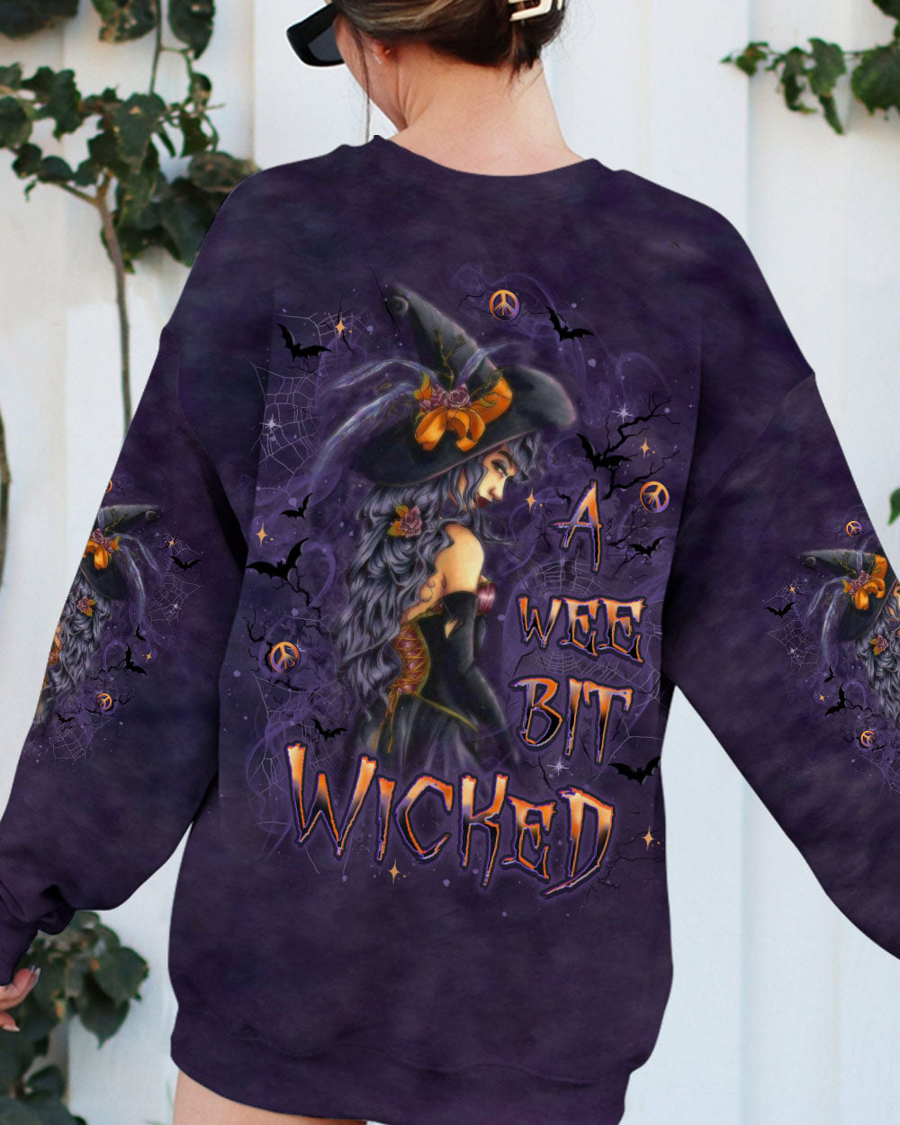 A Wee Bit Wicked Witch Shirt | All Over Print Front view of the a wee bit wicked witch shirt styled with jeans, perfect for casual Halloween gatherings.