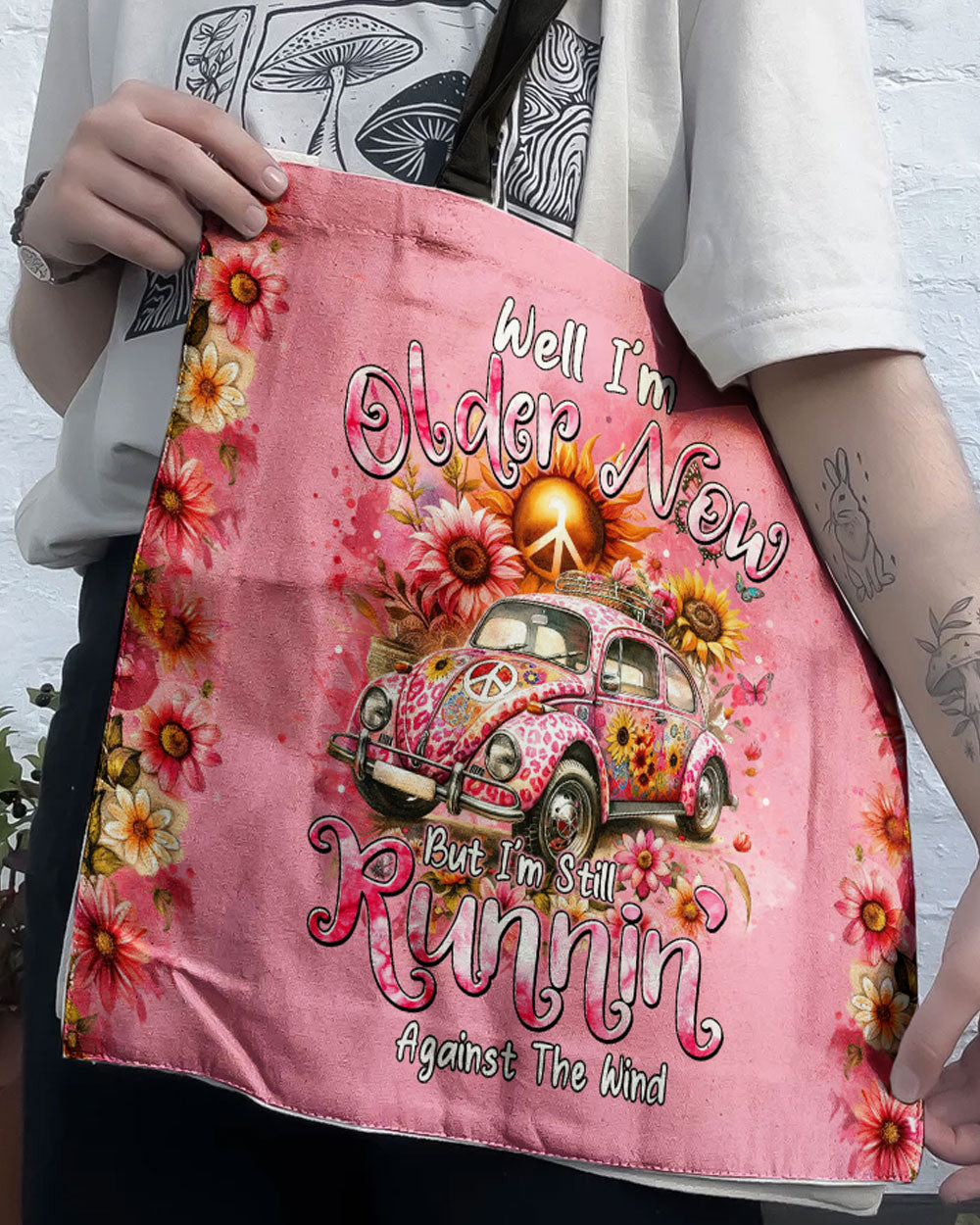 Running Against the Wind Tote Bag Front view of the running against the wind tote bag featuring a colorful floral design and vintage car on a pink background.