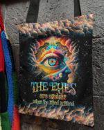 Front view of the eyes are useless tote bag featuring colorful cosmic design and bold text.